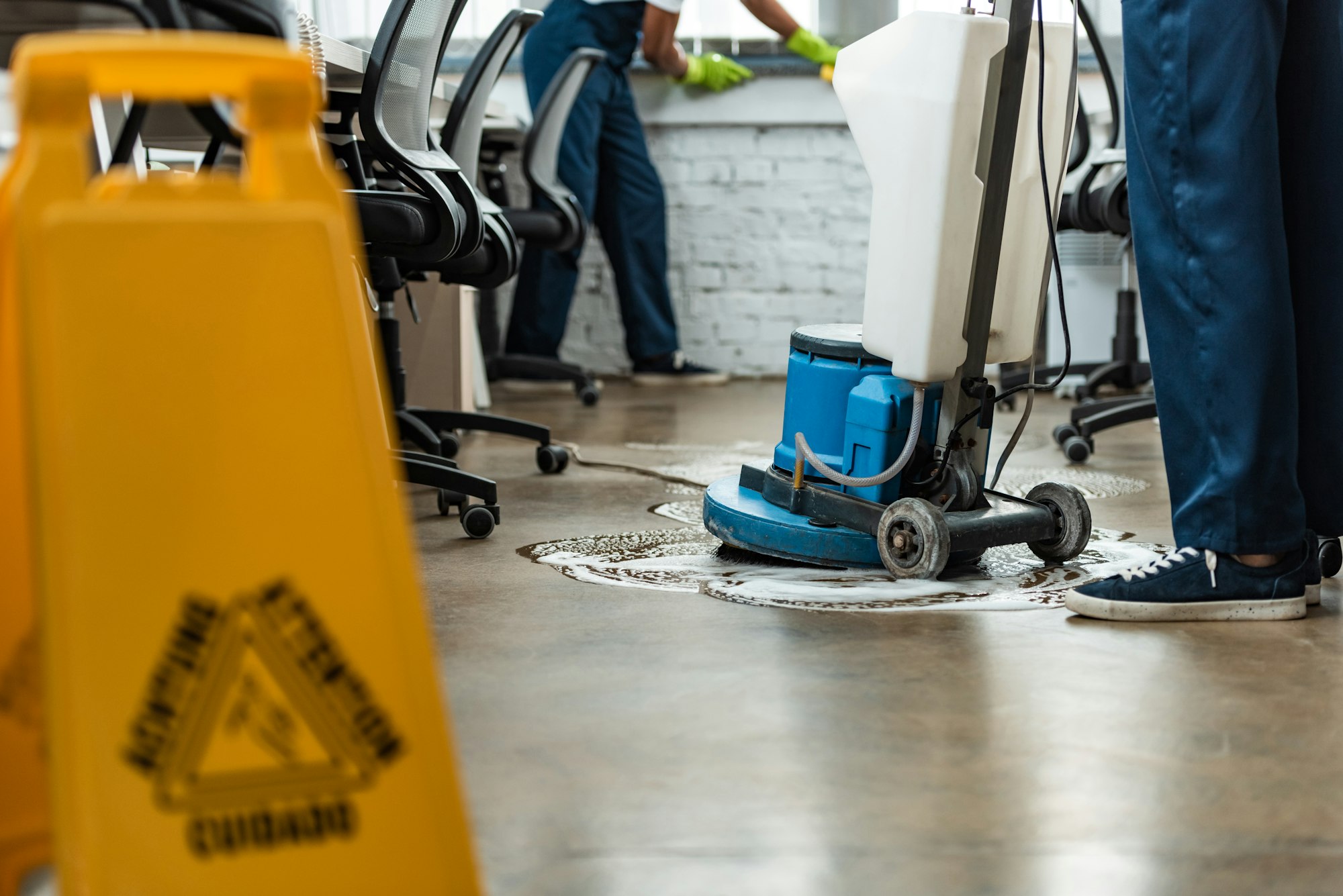 cropped view of cleaner washing floor with cleaning machine near colleague